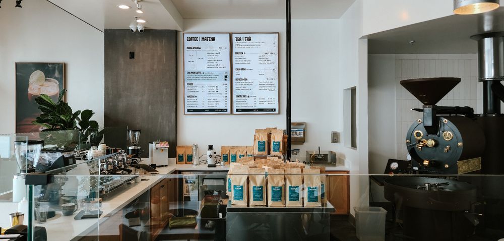 The Phin Cafe roastery counter, bags of coffee on the bar with the drum roaster behind